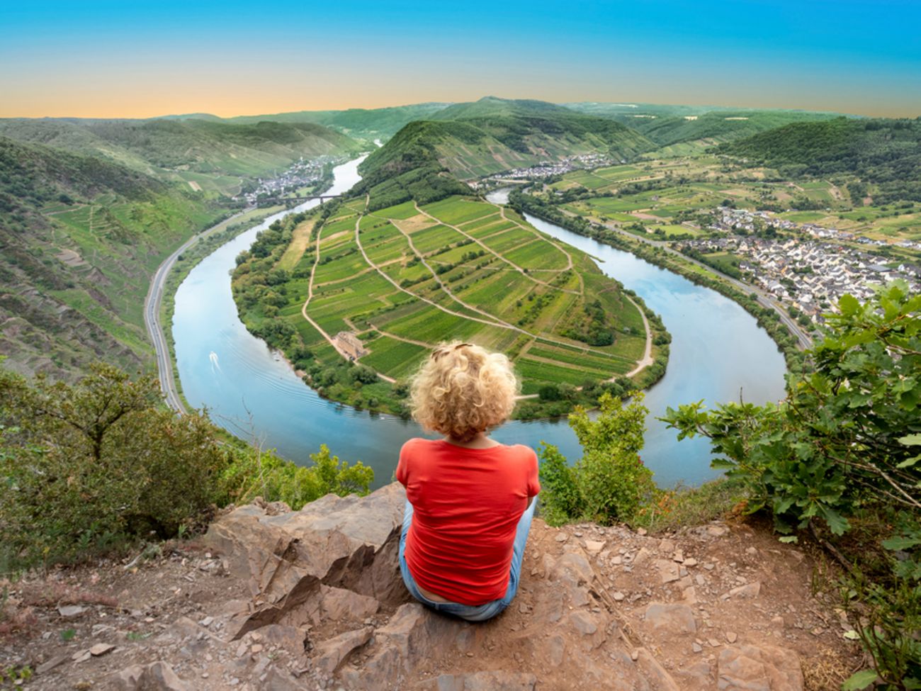 Flottenübersicht River Routen Crew Mitglied eines Flussschiffes sitzt auf einem Berg und schaut auf einen Fluss herunter